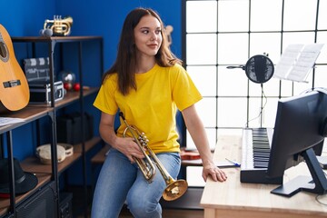 Young woman musician holding trumpet at music studio