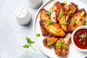 Chicken wings in bbq sauce on craft plate. Top view, close up on white stone table.