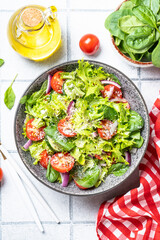 Green vegetable salad with fresh leaves. Healthy food, diet menu. Top view on white tile background.