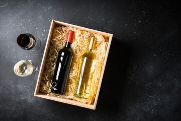 Red and white wine in wooden box at black background. Top view with copy space.