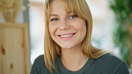 Young blonde woman smiling confident sitting on table at coffee shop