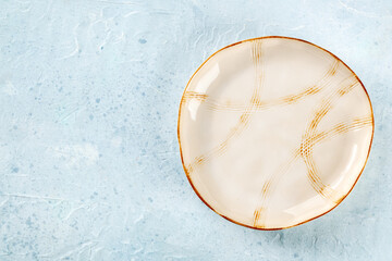 An empty plate with a gold rim, shot from above on a slate background with a place for text