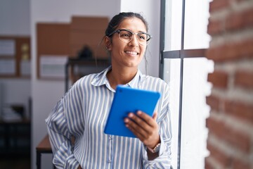 Young beautiful hispanic woman business worker smiling confident using touchpad at office