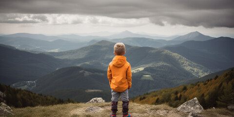 A young child hiker stares out of a scenic mountain view, large hilly landscape, orange coat jacket