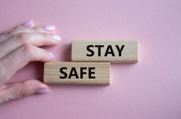 Stay Safe symbol. Concept word Stay Safe on wooden blocks. Businessman hand. Beautiful pink background. Business and Stay Safe concept. Copy space