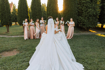 Beautiful elegant slim smiling bridesmaids in delicate pink beige summer dress on the wedding...