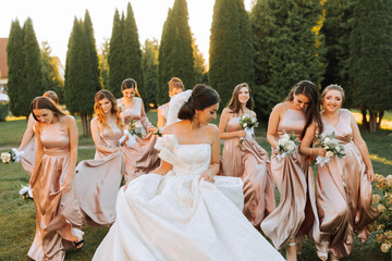 Beautiful elegant slim smiling bridesmaids in delicate pink beige summer dress on the wedding...