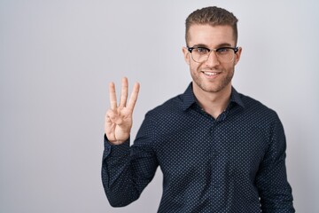 Fototapeta premium Young caucasian man standing over isolated background showing and pointing up with fingers number three while smiling confident and happy.