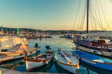 A view at sunset past dinghies moored in the harbour in the town of Izola, Slovenia in summertime