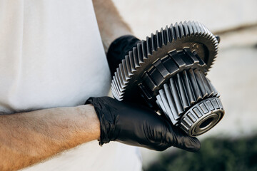 Man holding in his hands car parts, spares or accessories. Parking intermediate gear, automatic...