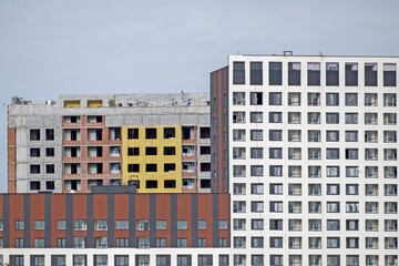Fragment of the facade of a multi-storey residential building under construction on a summer day