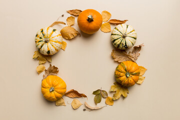 Autumn composition Pumpkins with fall leaves over coloredbackground. Top view with copy space