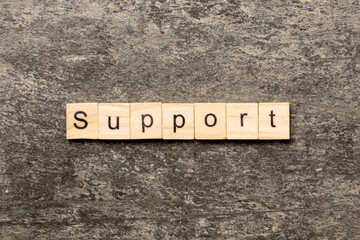 Fototapeta premium Support word written on wood block. Support text on cement table for your desing, concept