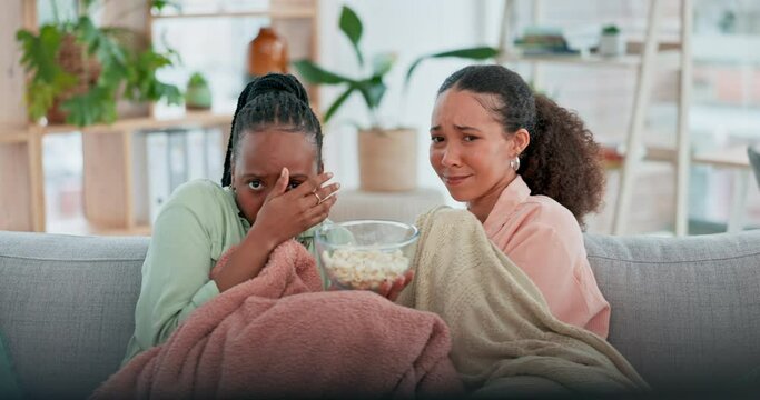 Women friends, watching tv and scared with popcorn, horror movies and shock face on sofa in home living room. Girl, eating and fear together for streaming subscription, show and lounge couch in house