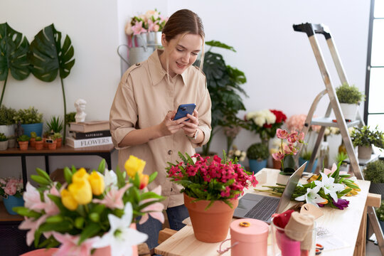 Young caucasian woman florist make photo to plant by smartphone at flower shop