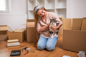 Happy modern ginger woman with braids moving into new home with her pet.