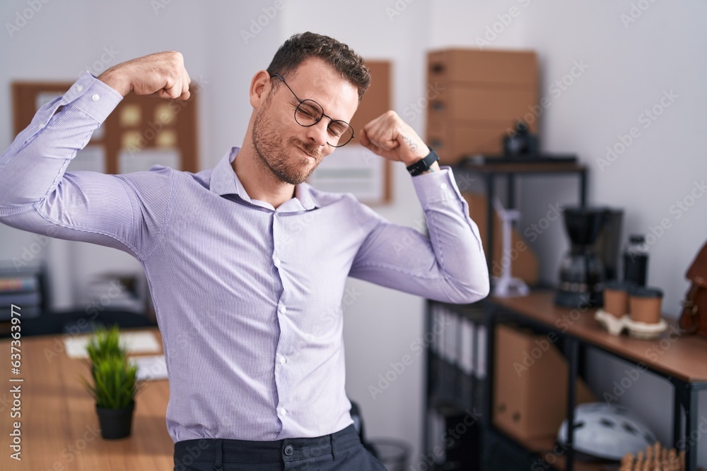 Sticker Young hispanic man at the office showing arms muscles smiling proud. fitness concept.