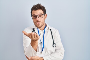 Young hispanic man wearing doctor uniform and stethoscope looking at the camera blowing a kiss with...