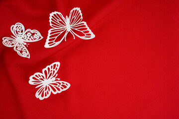 Close-up shot of crumpled red satin texture background and butterflies paper cutting with copy space for your design.