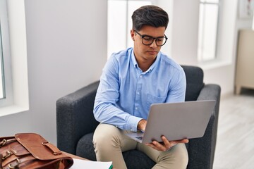 Young hispanic man psychologist using laptop at psychology clinic
