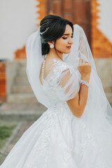 Beautiful bride in a fashionable wedding dress on a natural background in the park. A stunning young bride is incredibly happy. Happy girl on her wedding day