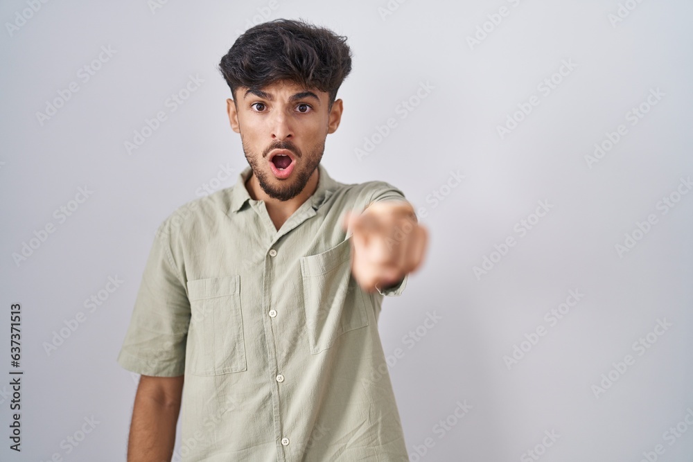 Poster arab man with beard standing over white background pointing displeased and frustrated to the camera,