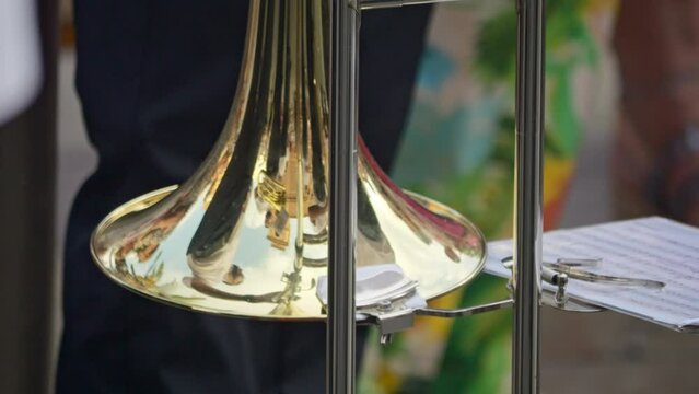 Trombonist performing in a parade; detail on trombone and music notes. Slow-motion footage.