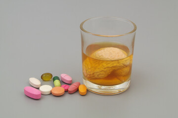 Glass of alcohol drink and human brain and drugs on gray background.	