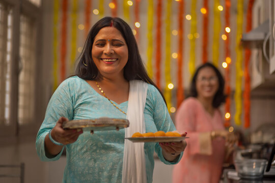 Sister in laws in the kitchen,preparing to serve sweets  during  the festival of Diwali
