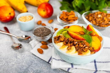 Bowl of granola with yogurt and fresh berries on a texture table. Yogurt berries, acai bowl, spirulina bowl. Healthy food, balanced breakfast. Strawberries, blueberries, kiwi, peach, almonds and chia.