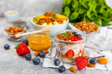 Bowl of granola with yogurt and fresh berries on a texture table. Yogurt berries, acai bowl, spirulina bowl. Healthy food, balanced breakfast. Strawberries, blueberries, kiwi, peach, almonds and chia.