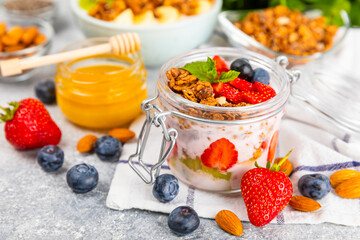 Bowl of granola with yogurt and fresh berries on a texture table. Yogurt berries, acai bowl, spirulina bowl. Healthy food, balanced breakfast. Strawberries, blueberries, kiwi, peach, almonds and chia.