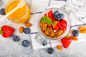 Bowl of granola with yogurt and fresh berries on a texture table. Yogurt berries, acai bowl, spirulina bowl. Healthy food, balanced breakfast. Strawberries, blueberries, kiwi, peach, almonds and chia.