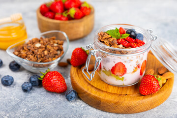 Bowl of granola with yogurt and fresh berries on a texture table. Yogurt berries, acai bowl, spirulina bowl. Healthy food, balanced breakfast. Strawberries, blueberries, kiwi, peach, almonds and chia.