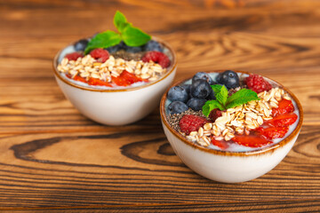 Fototapeta na wymiar Bowl of granola with yogurt and fresh berries on a texture table. Yogurt berries, acai bowl, spirulina bowl. Healthy food, balanced breakfast. Strawberries, blueberries, kiwi, peach, almonds and chia.