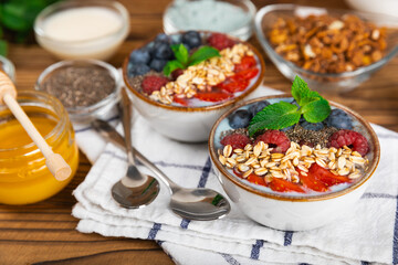 Bowl of granola with yogurt and fresh berries on a texture table. Yogurt berries, acai bowl, spirulina bowl. Healthy food, balanced breakfast. Strawberries, blueberries, kiwi, peach, almonds and chia.