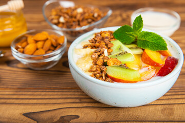 Bowl of granola with yogurt and fresh berries on a texture table. Yogurt berries, acai bowl, spirulina bowl. Healthy food, balanced breakfast. Strawberries, blueberries, kiwi, peach, almonds and chia.