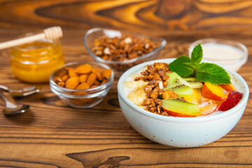 Bowl of granola with yogurt and fresh berries on a texture table. Yogurt berries, acai bowl, spirulina bowl. Healthy food, balanced breakfast. Strawberries, blueberries, kiwi, peach, almonds and chia.