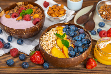 Bowl of granola with yogurt and fresh berries on a texture table. Yogurt berries, acai bowl, spirulina bowl. Healthy food, balanced breakfast. Strawberries, blueberries, kiwi, peach, almonds and chia.