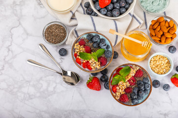 Bowl of granola with yogurt and fresh berries on a texture table. Yogurt berries, acai bowl, spirulina bowl. Healthy food, balanced breakfast. Strawberries, blueberries, kiwi, peach, almonds and chia.