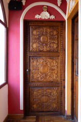 Beautiful old carved wooden door in old building, with walls painted pink and orange, La Paz, Bolivia