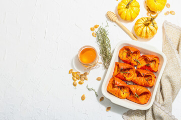 Fototapeta na wymiar Oven baked pumpkin slices with honey, rosemary and seeds. Vegan food, trendy hard light, dark shadow