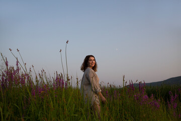 middle aged woman in a field with wildflowers in the evening at sunset.   Slow life. Enjoying the little things. copy space. Amazing chill moment