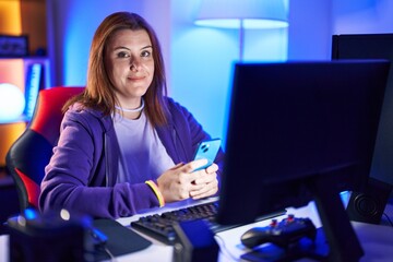 Obraz premium Young beautiful plus size woman streamer using computer and smartphone at gaming room