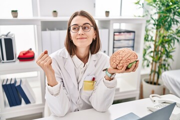 Young caucasian doctor woman holding brain as mental health concept screaming proud, celebrating victory and success very excited with raised arms