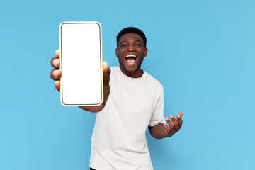 african american guy in white t-shirt shows blank screen of smartphone and rejoices in victory on...