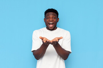 african american guy in white t-shirt holds empty hands in front of him and rejoices with his mouth open