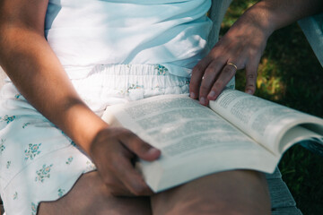 Naklejka premium Manos femeninas sosteniendo un libro al aire libre