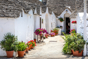Fototapeta na wymiar Alberobello, Italy - July 21, 2021: The Trulli of Alberobello in Apulia in Italy. These typical houses with dry stone walls and conical roofs are unique to the world