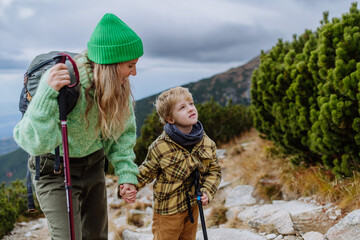 Active mother with little son hiking together in autumn mountains.